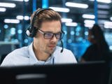 Ung man sitter med headset vid sin datorskärm.